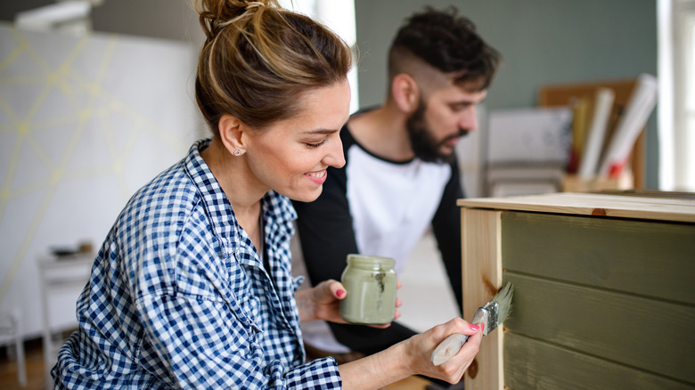 Two people painting furniture