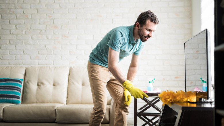 man dusting tv