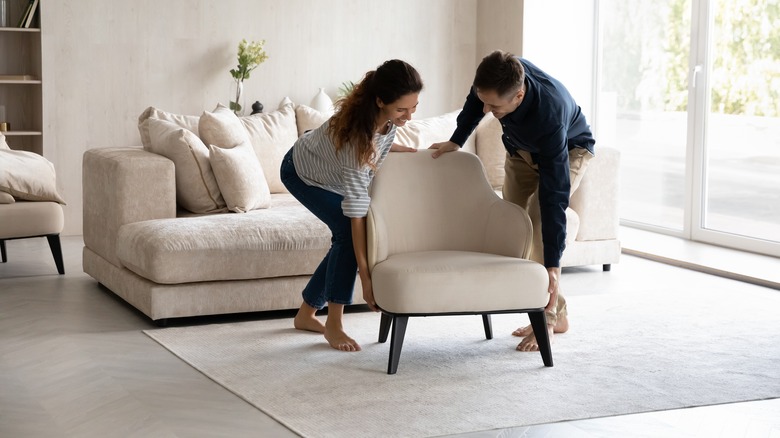 People moving white armchair