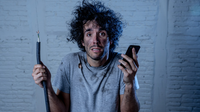 man holding phone and cable