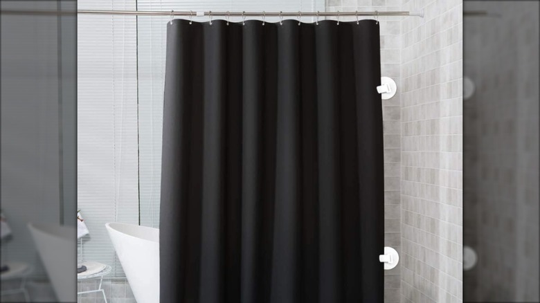 Black shower curtain clipped to the wall with suction cups to keep it in place in a modern bathroom