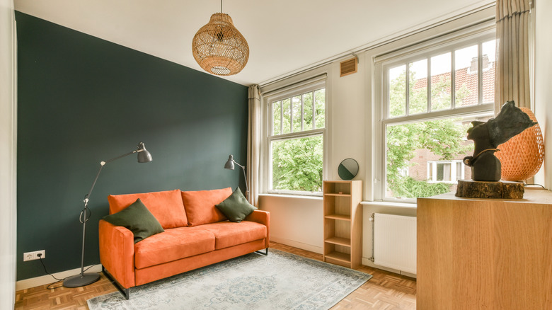 Living room with dark green accent wall and orange couch