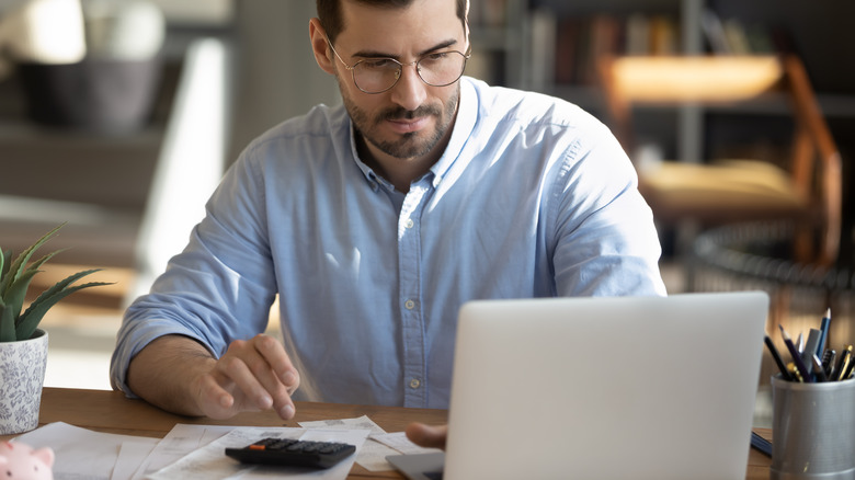 man calculating bills on calculator