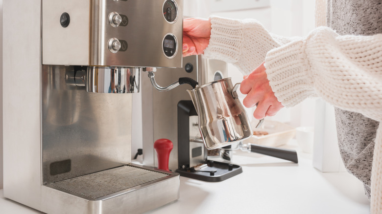 Person steaming milk using an espresso maker