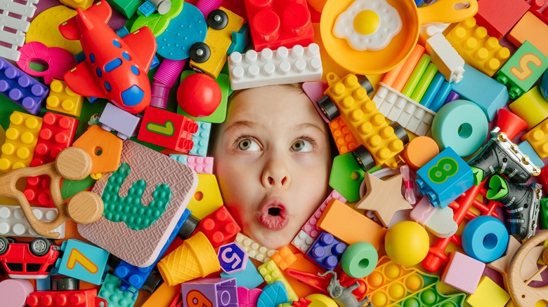 child surrounded by toys