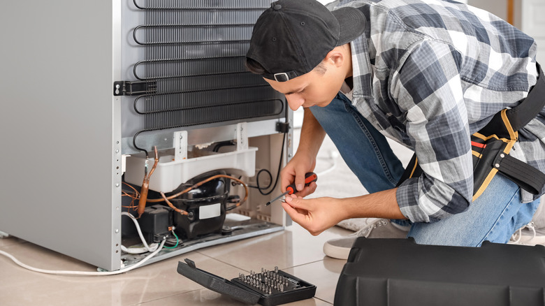 technician repairing refrigerator