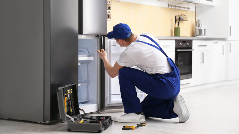 technician repairing refrigerator