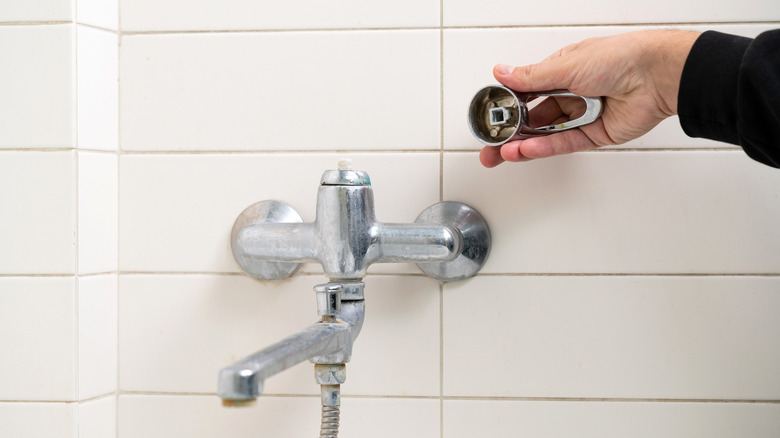 Man holding a broken shower faucet handle