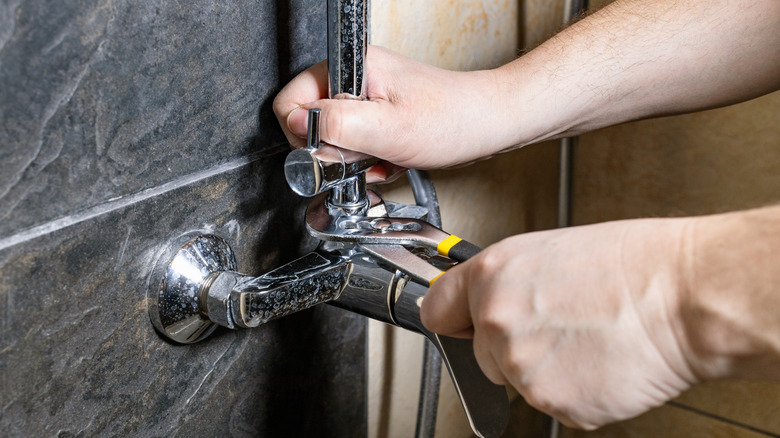 Person unscrewing a diverter valve in shower