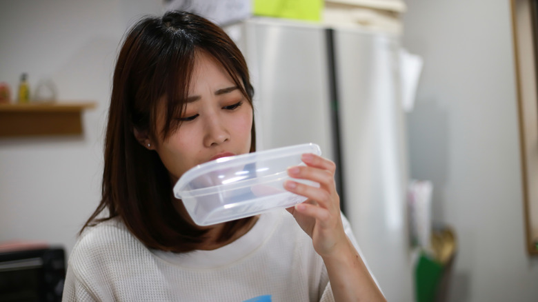 Woman smelling Tupperware container