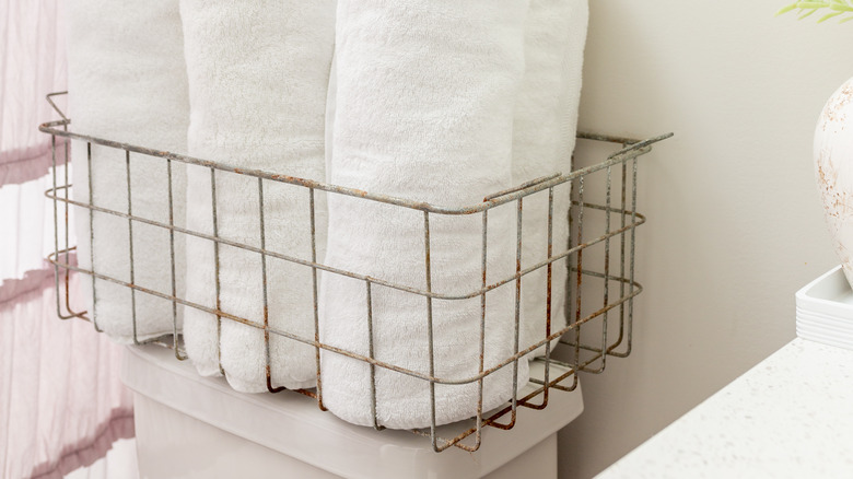 Basket of towels on top of toilet