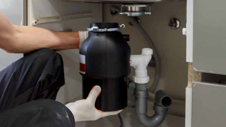 man installing garbage disposal