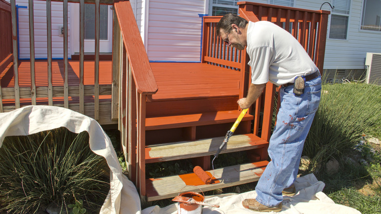 man staining wooden deck