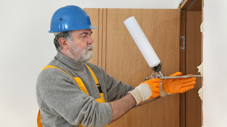 Construction worker caulking wooden door