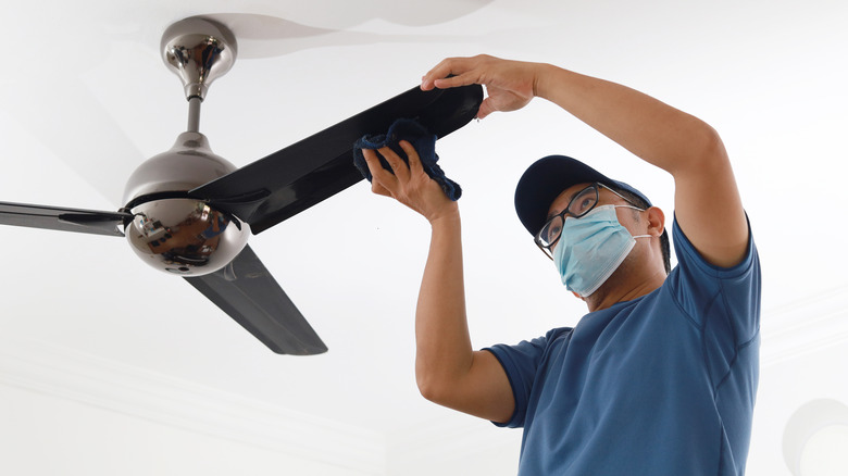 Man cleaning ceiling fan