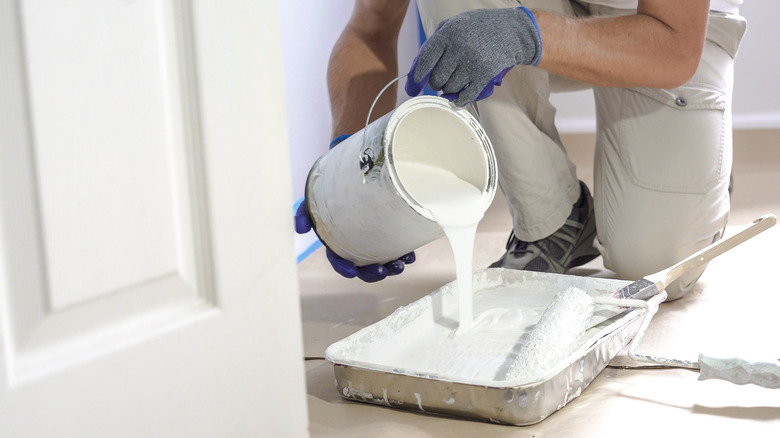 man pouring paint in tray