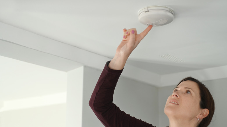 Woman testing smoke alarm