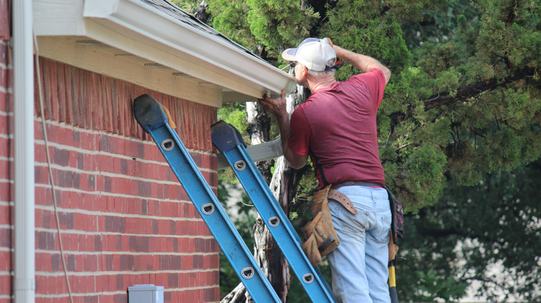 Man repairing exterior of house