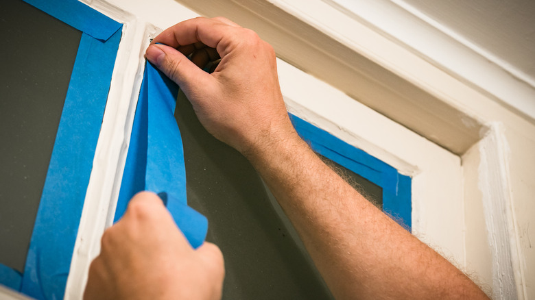 Person applying painter's tape to window