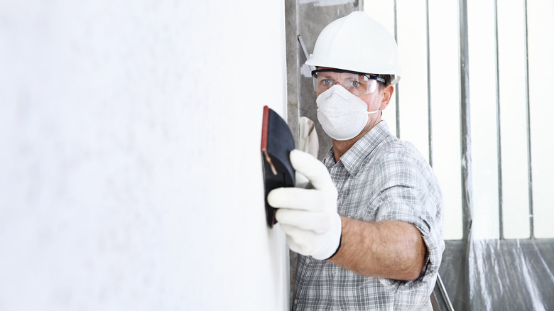 Person sanding a wall