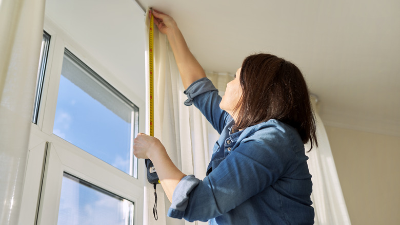 Woman measuring window for curtains