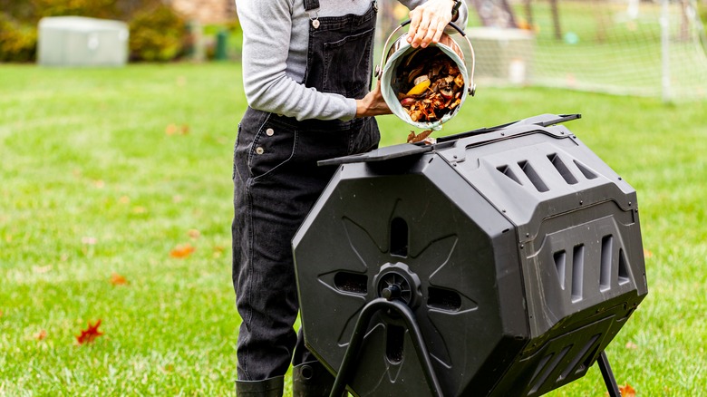 Person adding to compost tumbler