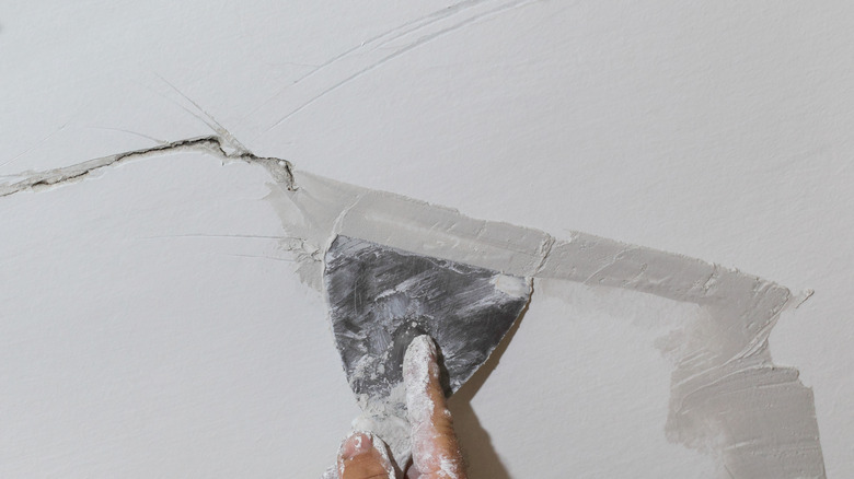 Person fixing crack in wall