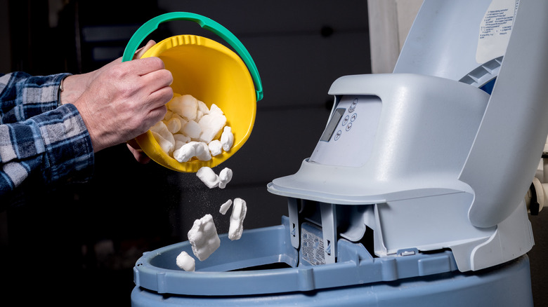 Hands pouring rock salt bucket