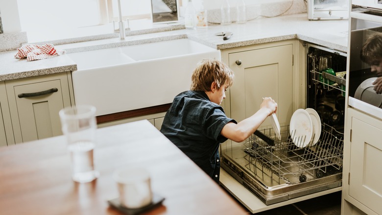 Boy loading the dishwasher