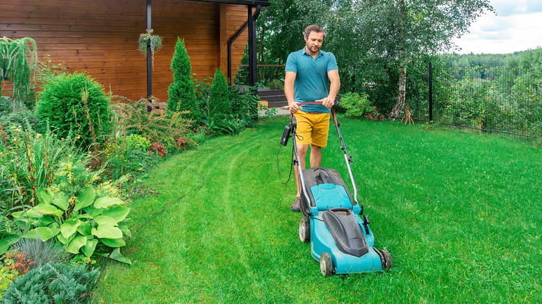 young man mowing grass