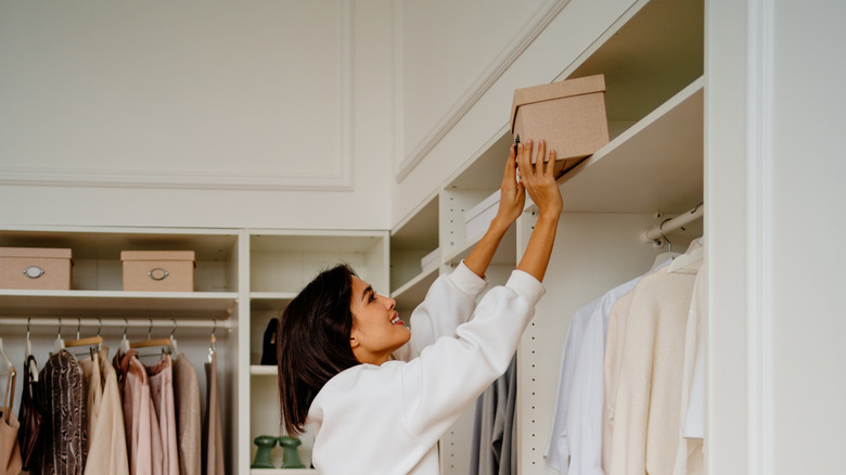 Lady storing box in wardrobe