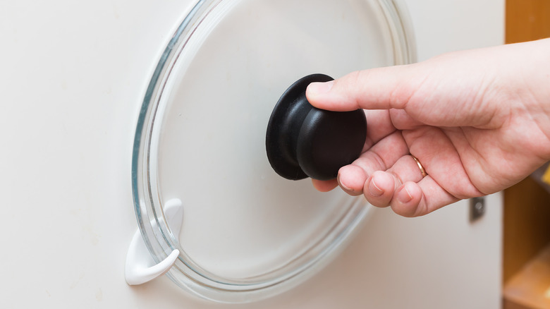 person placing lid inside hook