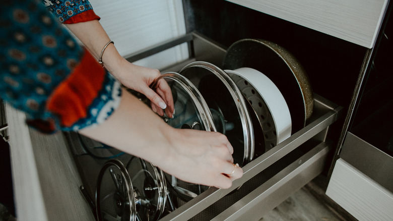 person placing lids in drawer