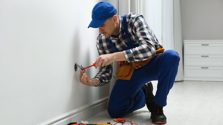 electrician working on wall outlet