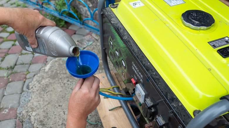 man filling generator with oil