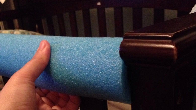 blue pool noodle acting as a cot rail bumper