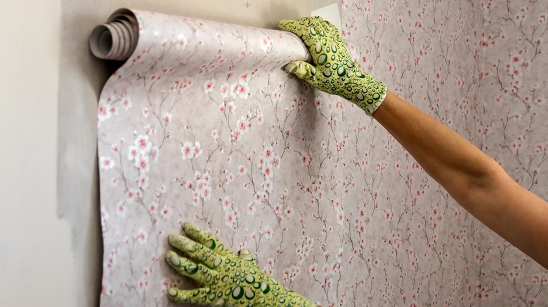 person installing wallpaper