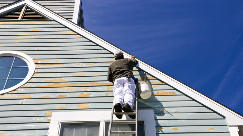 Person painting house exterior