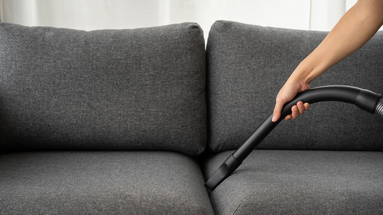 Person vacuuming sofa