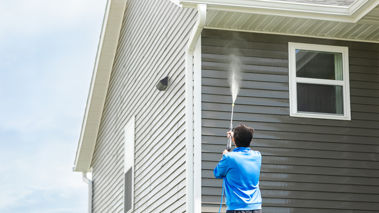 man cleaning mold of siding