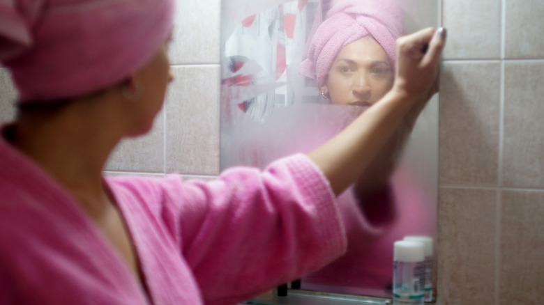 Woman examines fogged mirror