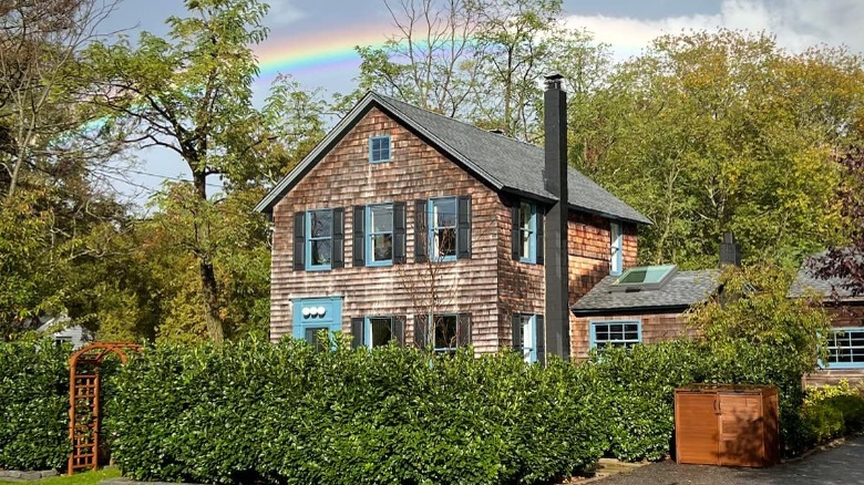 Wood-shingled house behind hedge