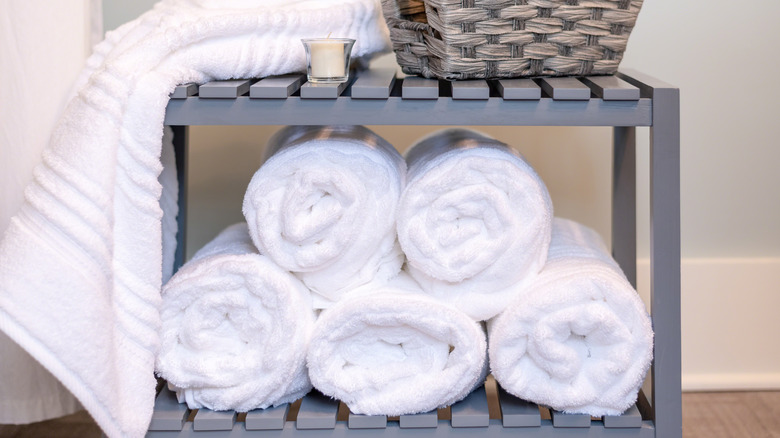 Rolled white towels on gray bench