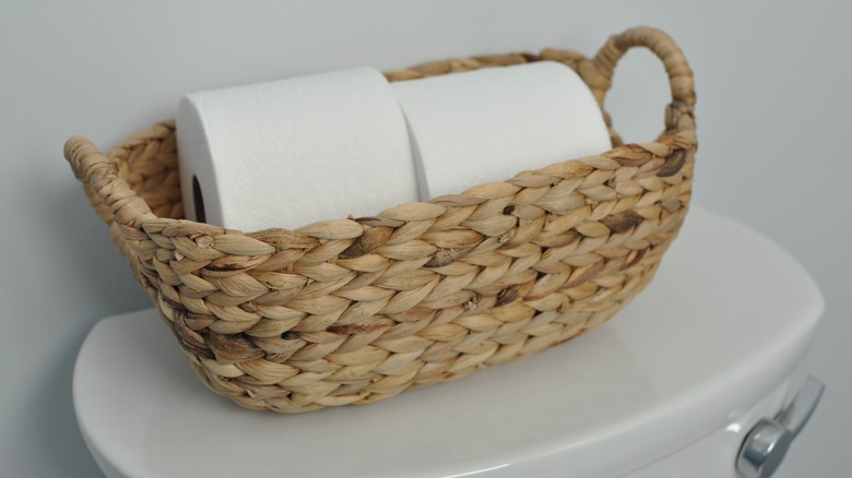 Basket with toilet paper on top of a toilet