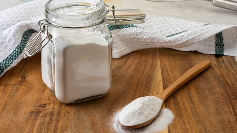 Jar and spoonful of soda crystals on a wooden table