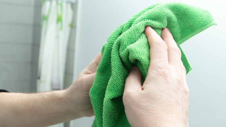 Man cleaning a mirror with green cloth