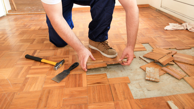 person lifting parquet wood flooring