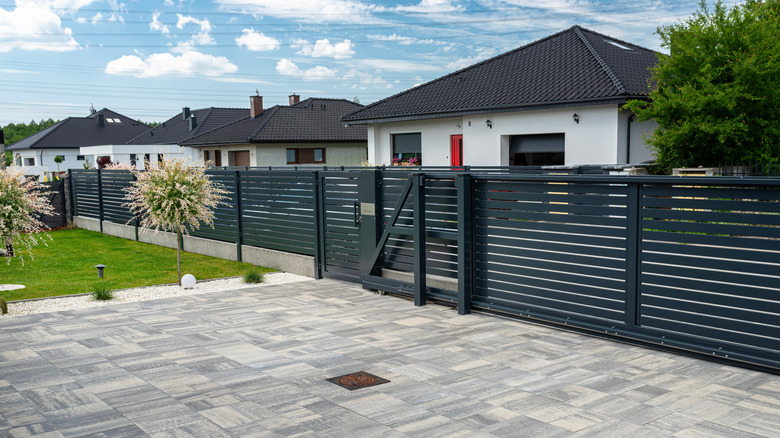 Front yard with horizontal black fence and paved driveway