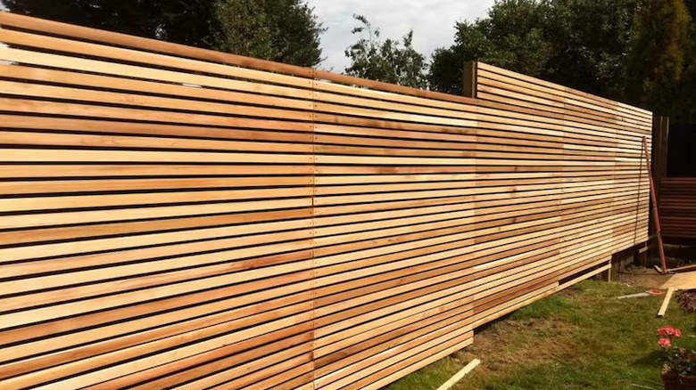 Timber fence with thin horizontal slats under construction