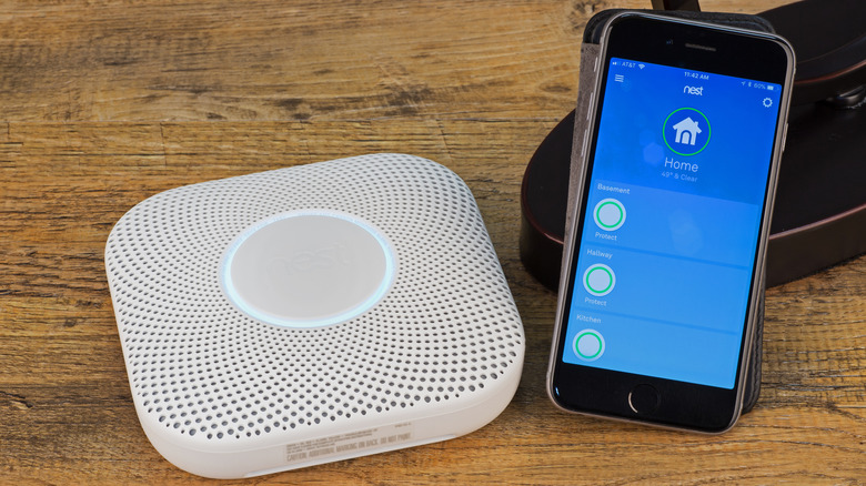 Phone next to smart smoke detector on table